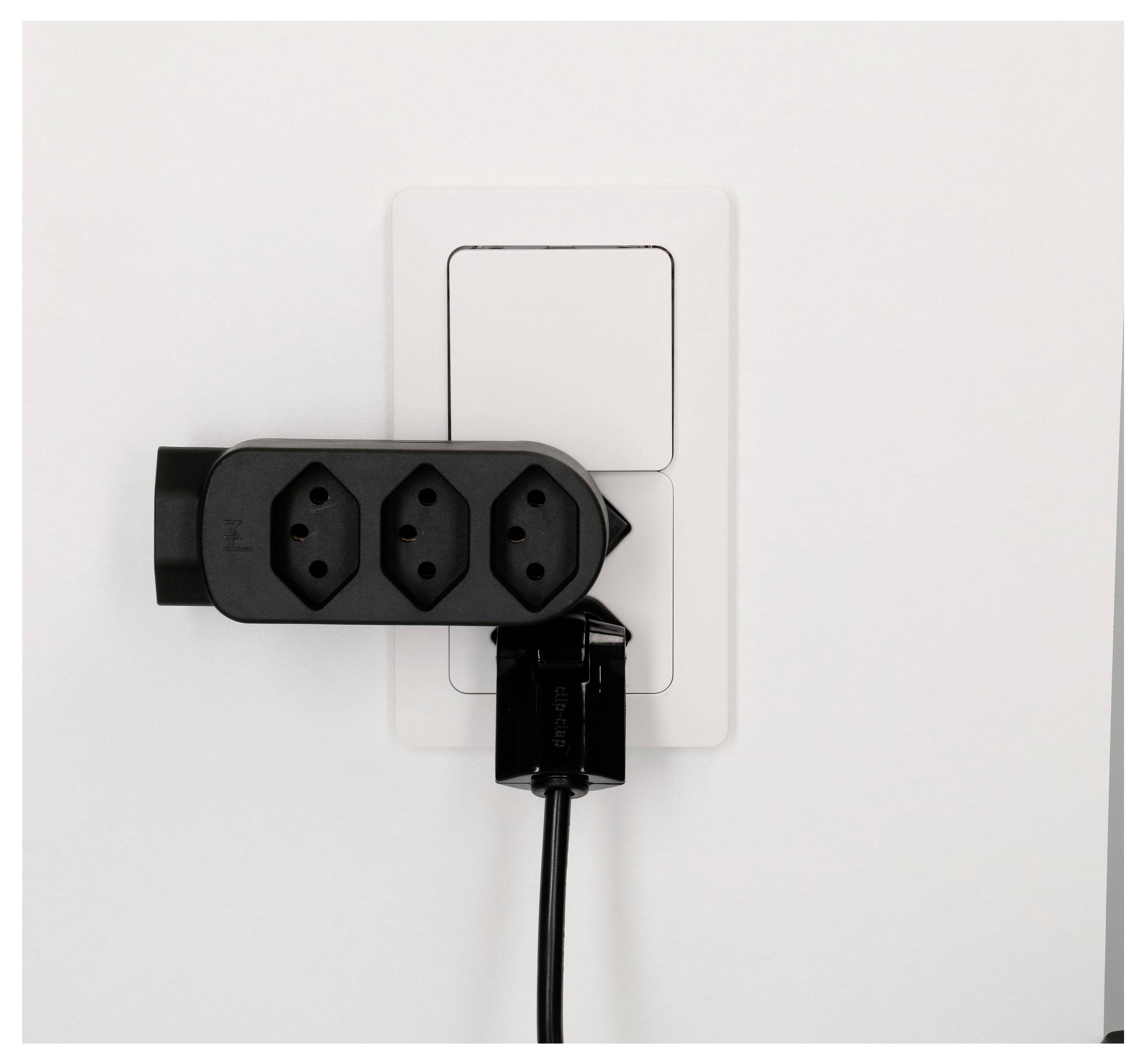 Schwarze Steckerleiste, die in eine weiße Wandsteckdose eingesteckt ist, mit einem Kabel, das nach unten hängt.