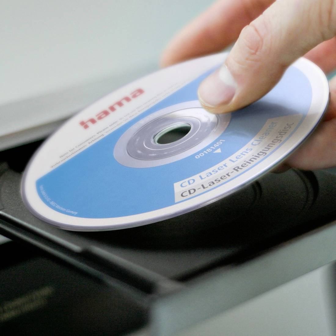 Hand legt eine Hama-CD mit der Beschriftung für CD-Laser-Objektivreinigung in das Laufwerksfach eines CD-Players.