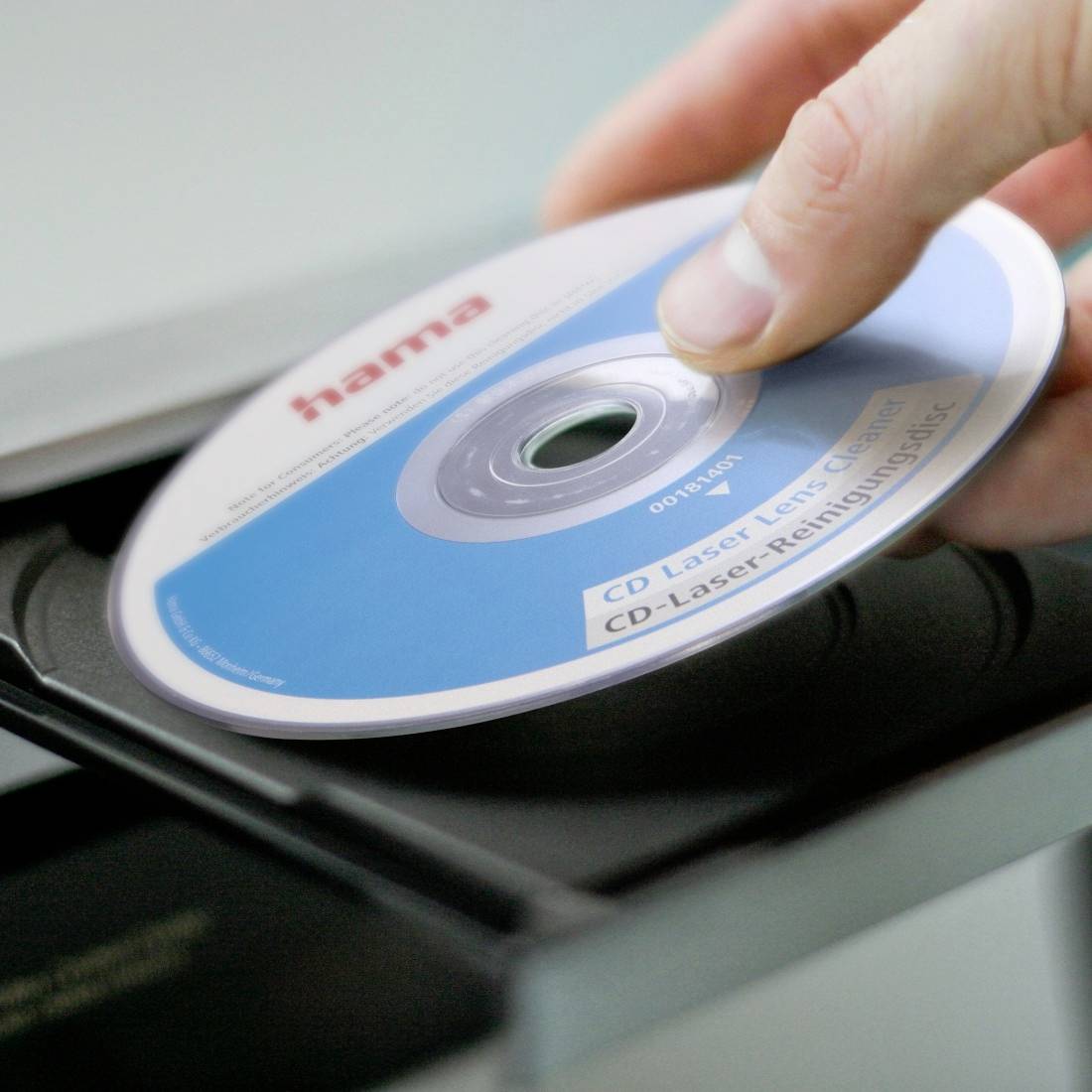 Hand legt eine Hama CD Laser-Linsen-Reiniger-Disc in ein CD-Player-Fach ein.