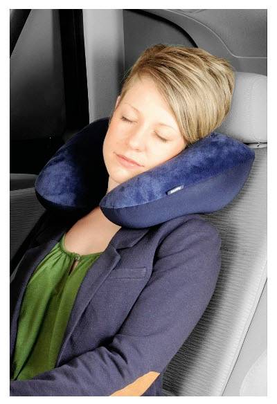 Schlafende Frau, die ein blaues U-förmiges Reisenkissen um den Hals trägt und einen Blazer trägt, auf einem Auto- oder Fahrzeugsitz sitzend.