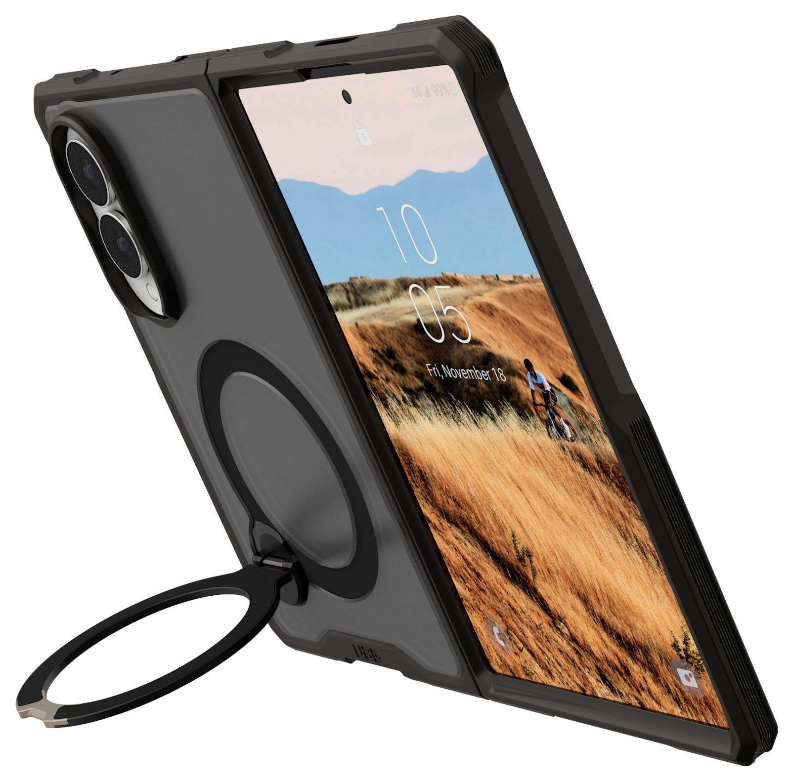 Schwarze robuste Smartphone-Schutzhülle mit Kameraausschnitt, kreisförmigem Ringständer und angebrachtem Handgriff, dargestellt beim Halten eines Telefons mit Landschafts-Hintergrundbild.