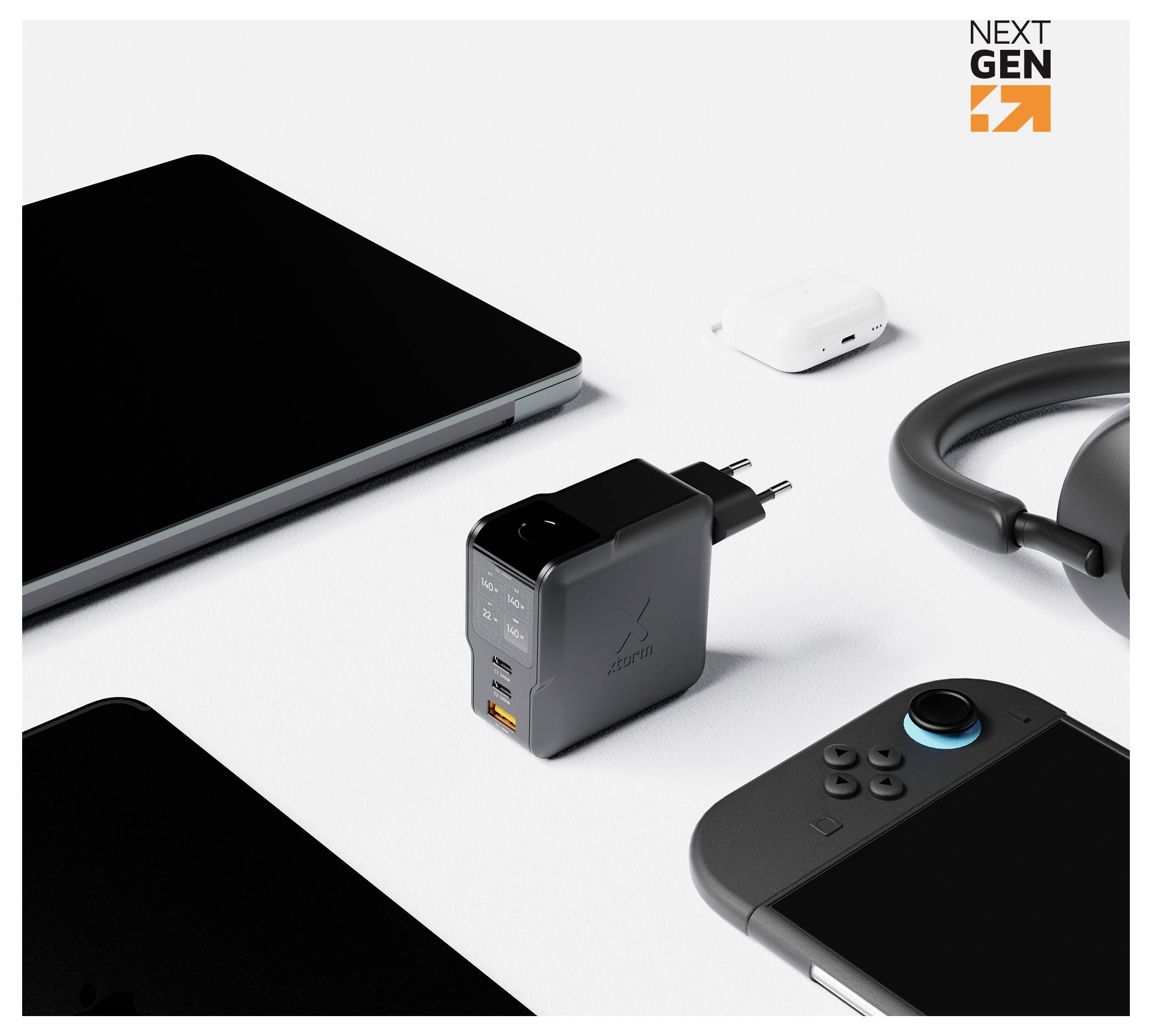 Draufsicht eines schwarzen Ladegerät-Adapters mit USB-Anschlüssen und Stecker, umgeben von einem Laptop, Ohrhörer-Etui, Kabel und Game-Controller auf weißem Hintergrund.
