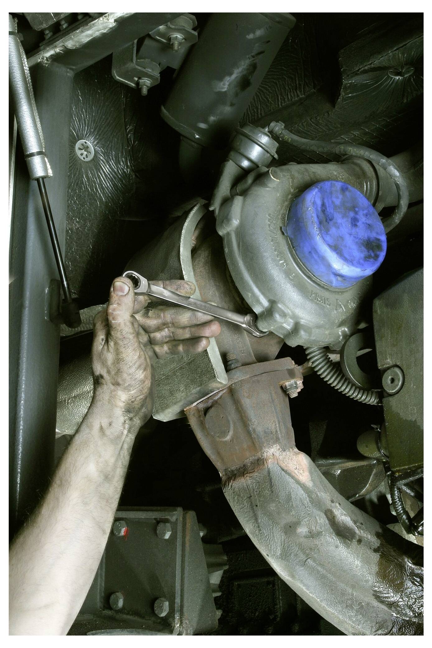 Eine Mechanikhand benutzt einen Schraubenschlüssel, um ein großes Industrieventil oder eine Pumpe in einem Maschinenraum zu warten.