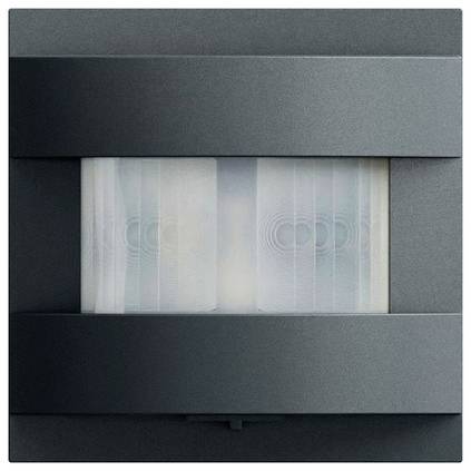 Abstraktes, an der Wand montiertes graues Gerät mit einem zentralen durchscheinenden Fenster, das zwei kreisförmige, sensorähnliche Elemente im Inneren zeigt.