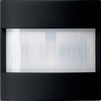 Ein schwarzes rechteckiges Panel mit einem zentralen mattweißen Fenster, das in zwei Scheiben unterteilt ist und dahinter schwache kreisförmige Muster zeigt.