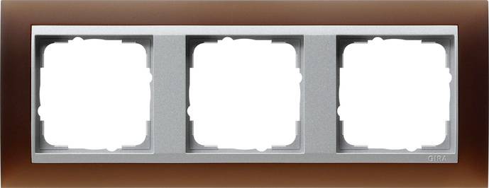 Dreifach-Wandschalterblende mit drei leeren quadratischen Schalteröffnungen an einer braunen Wand.
