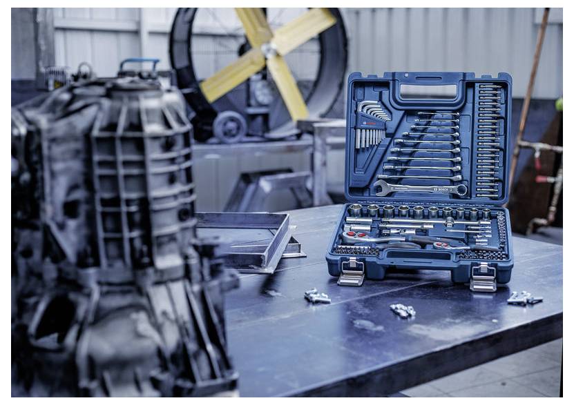 Offener blauer Mechanikerkoffer mit Schraubenschlüsseln und Stecknüssen auf einer Werkbank in einer Garage oder Werkstatt.