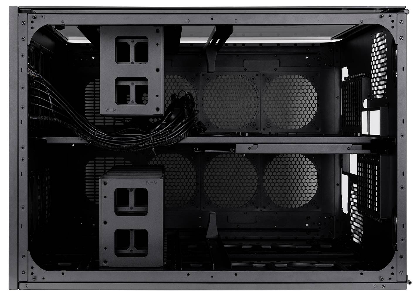 Leeres schwarzes Computergehäuse-Inneres mit Laufwerkschächten, Kabelführung und gelochten Paneelen für Luftströmung.