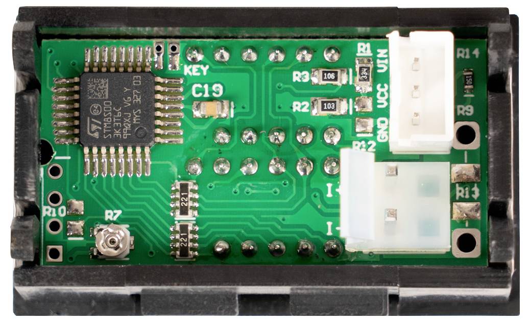 Nahaufnahme eines grünen elektronischen Leiterplattenmoduls mit einem Mikrochip, Steckverbindern und beschrifteten Komponenten in einem schwarzen Gehäuse.