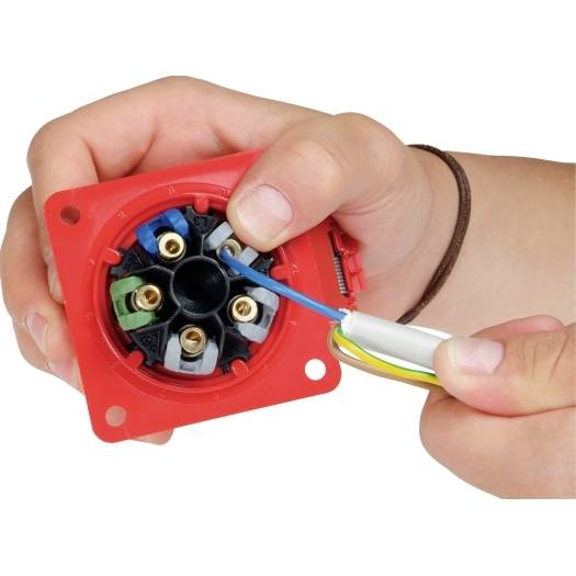 Hände verdrahten einen roten Elektrostecker, führen ein blaues Kabel in den Klemmblock ein.