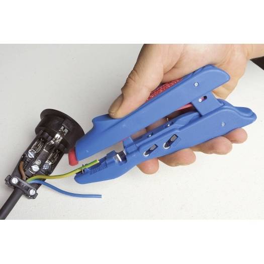 Hand, die einen blauen Abisolierzangen verwendet, um die Isolierung von einem an einem Stecker angeschlossenen Stromkabel zu entfernen.