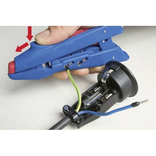 Hand, die einen blauen Abisolier-/Crimpwerkzeug an einem Kabelstecker verwendet, mit roten Pfeilen, die anzeigen, wo zu drücken ist.