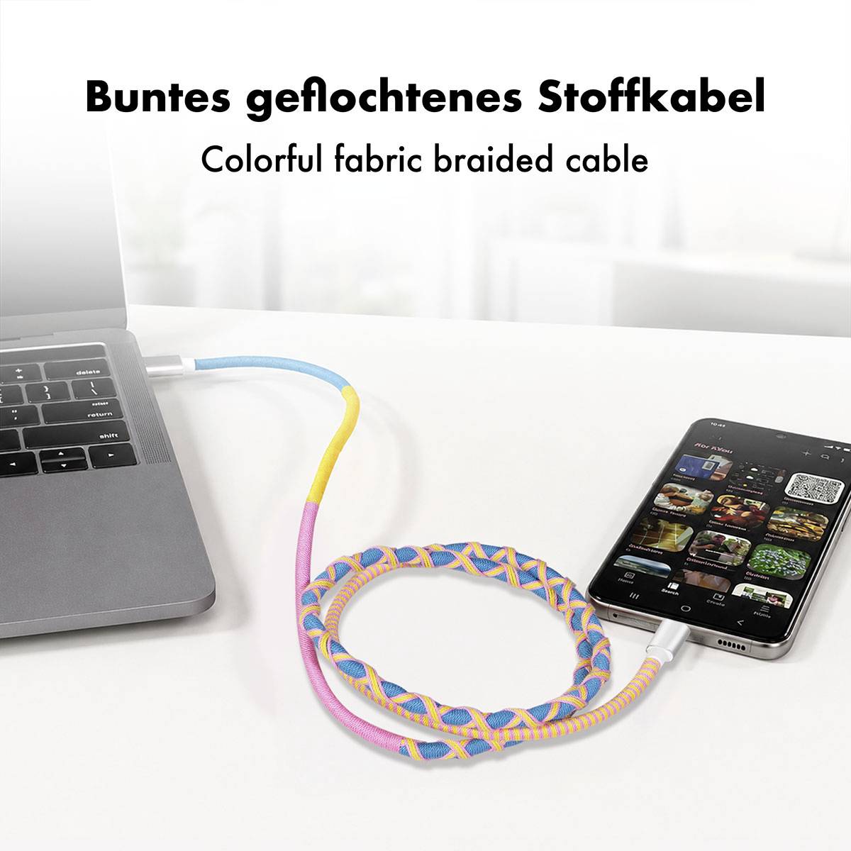 Buntes geflochtenes Ladekabel verbindet einen Laptop und ein Smartphone auf einem weißen Schreibtisch, mit dem Text „Buntes geflochtenes Stoffkabel" und „Colorful fabric braided cable".