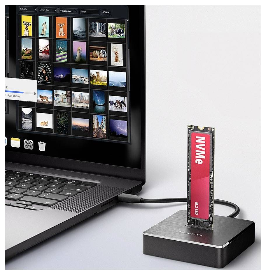 Laptop, der über ein Kabel mit einer NVMe-SSD in einer kleinen externen Festplattenschleuse verbunden ist, mit einer auf dem Bildschirm geöffneten Fotogalerie.