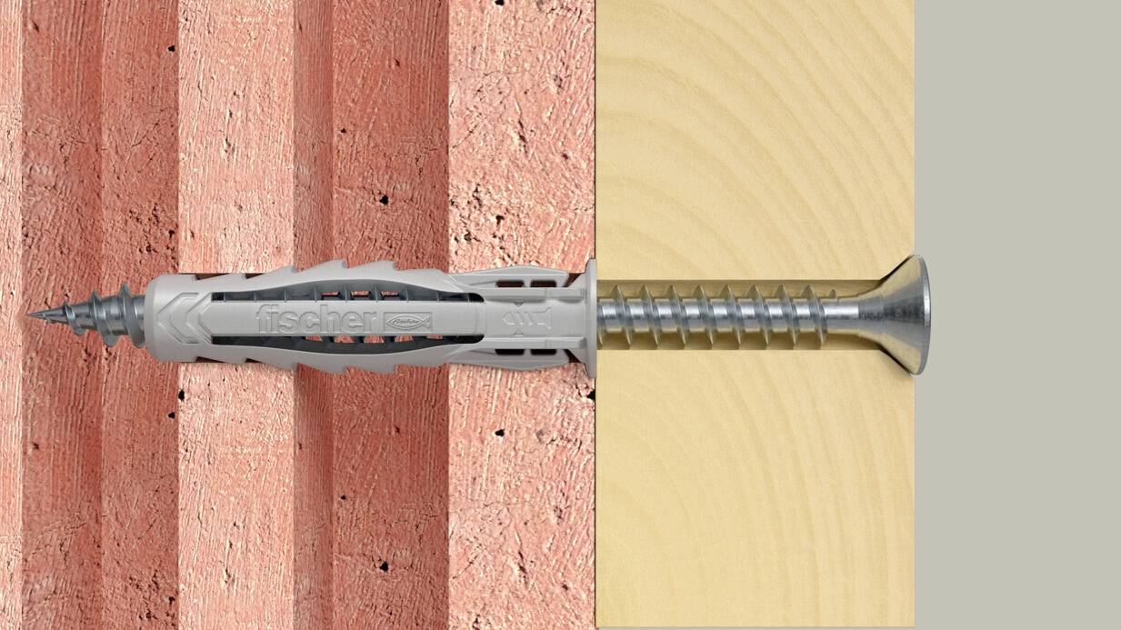 Wandanker und Schraube, die durch eine Ziegelmauer in Holz installiert sind und die Griffigkeit des Befestigungselements und die Befestigung über mehrere Materialien hinweg zeigen.