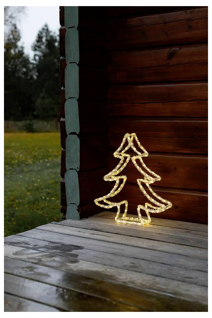 Leuchtender beleuchteter Weihnachtsbaum als Dekoration auf einer Holzveranda neben einer Hütte, mit unscharfem Außenhintergrund.