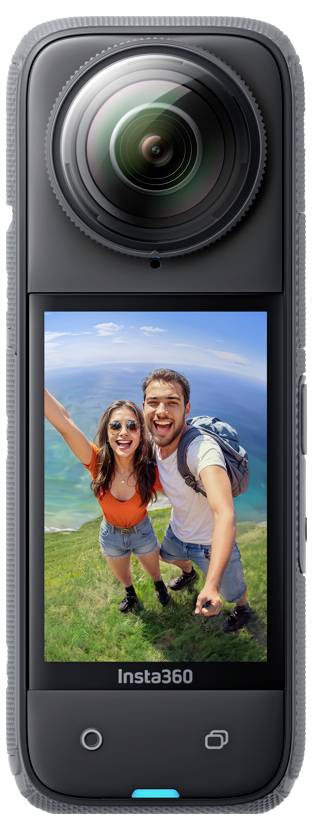Eine tragbare Insta360-Kamera mit einem großen Objektiv und einem Bildschirm, auf dem zwei lächelnde Wanderer ein Selfie auf einem grünen Hügel unter blauem Himmel machen.