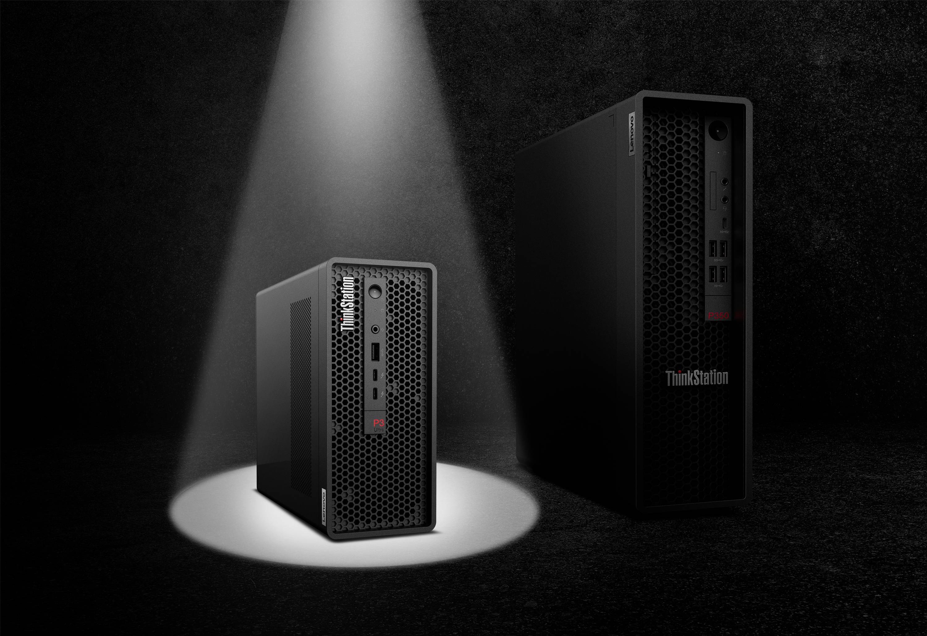 Zwei Lenovo ThinkStation-Desktop-Türme auf einer dunklen Bühne, einer im Vordergrund angestrahlt und einer größeren im Hintergrund.