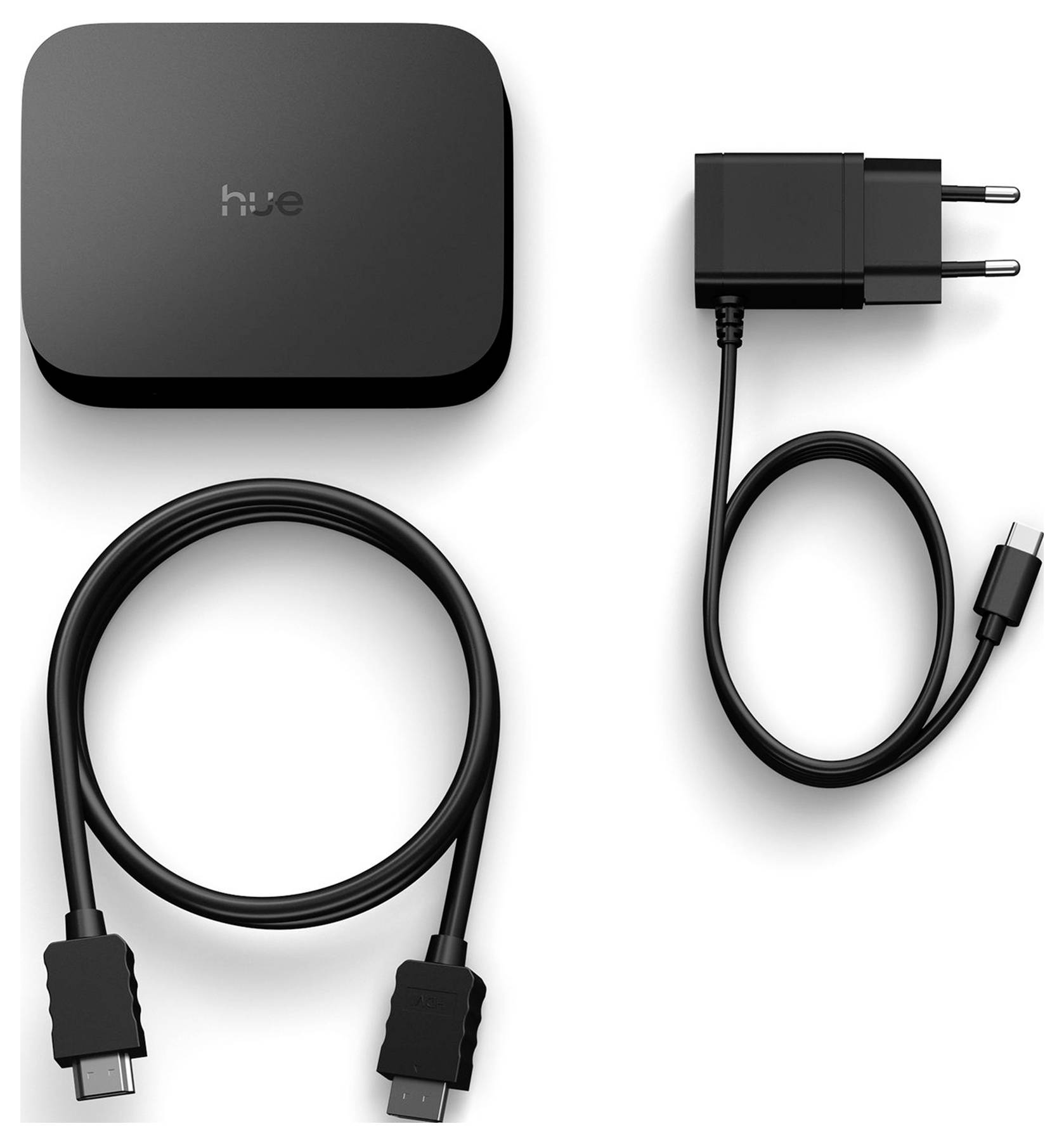 Schwarzes Hue-Gerät mit Netzteil und USB-Kabel auf weißem Hintergrund angeordnet.