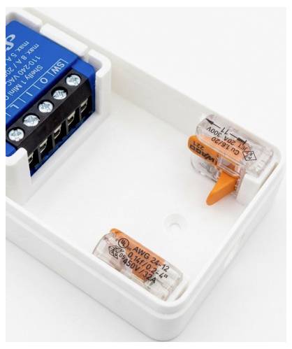 Nahaufnahme einer weißen elektrischen Verteilerdose mit einer blauen Klemmleiste und zwei transparenten orangen Hebelbeschlägen im Inneren.