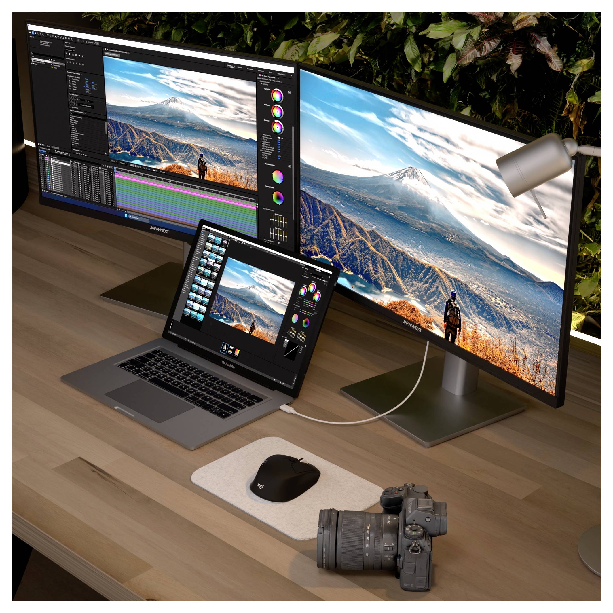 Eine Dual-Monitor-Kreativwerkstatt mit einem Laptop und einer Kamera auf einem Holzschreibtisch, auf den Bildschirmen werden Foto- und Videobearbeitungssoftware sowie eine Berglandschaft angezeigt.