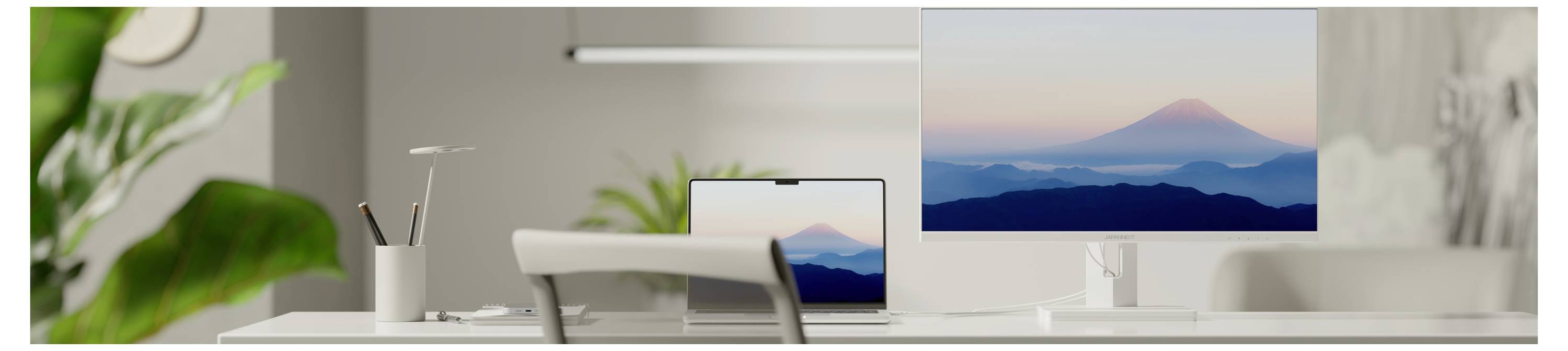 Minimales Homeoffice mit einem Schreibtisch, einem Stuhl, einer Pflanze und einem Computermonitor, auf dem eine Berglandschaft bei Sonnenuntergang angezeigt wird.