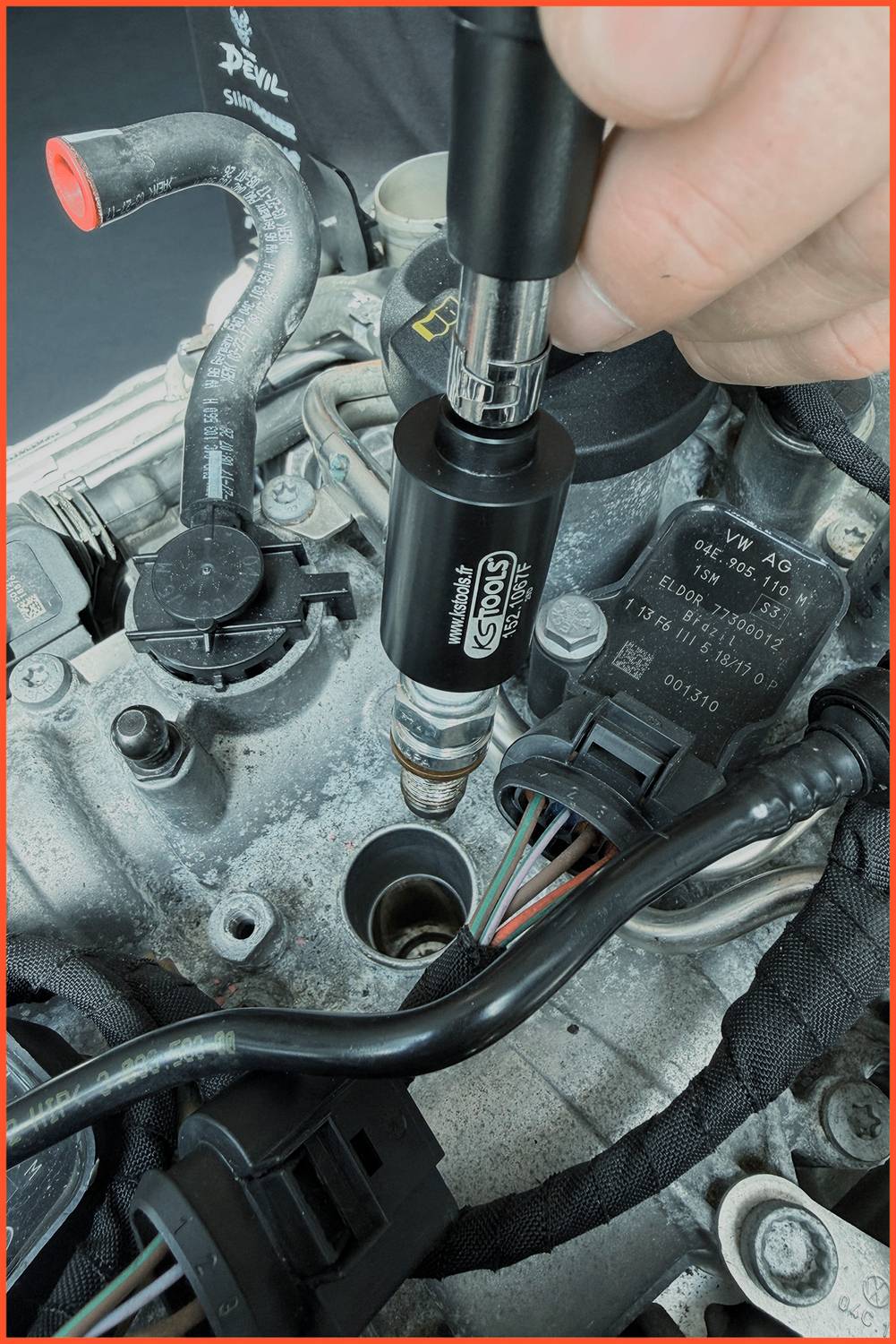 Ein Mechaniker verwendet einen Stecknussschlüssel, um eine Zündkerze aus dem Zylinderkopf eines Motors zu entfernen, wobei Verdrahtung und Motorkomponenten sichtbar sind.