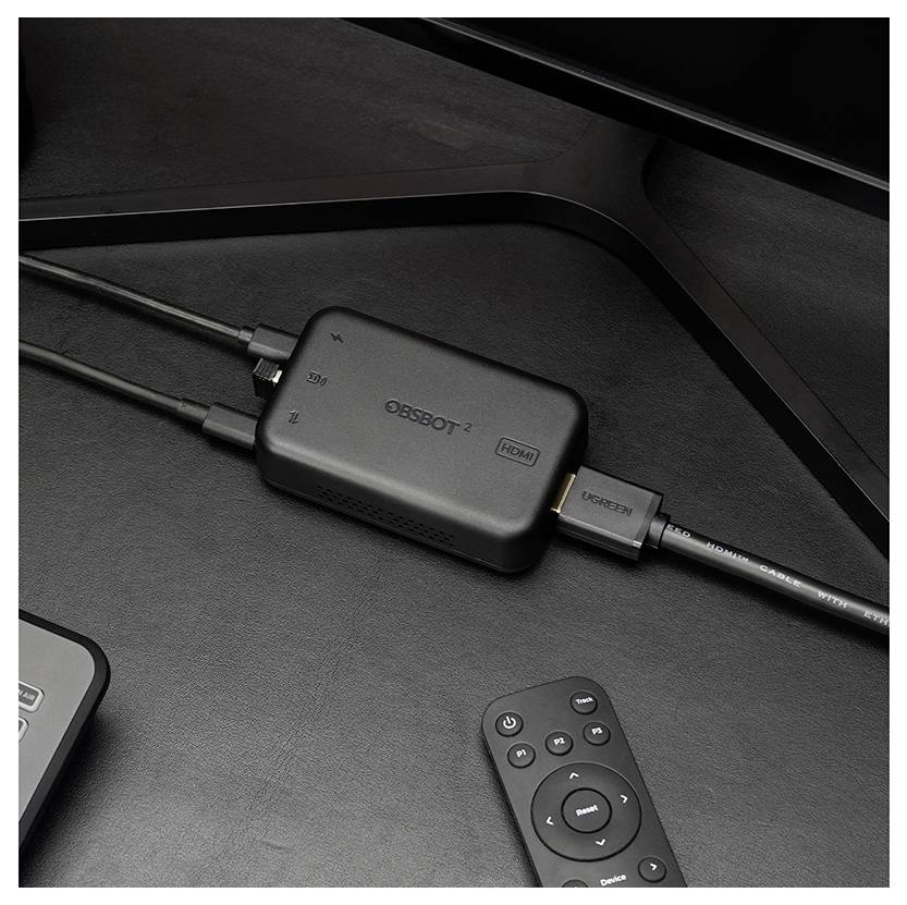 Schwarze OTT-Set-Top-Box mit zwei angeschlossenen Kabeln, USB-Ausgang und einer kleinen Fernbedienung auf einem dunklen Schreibtisch.