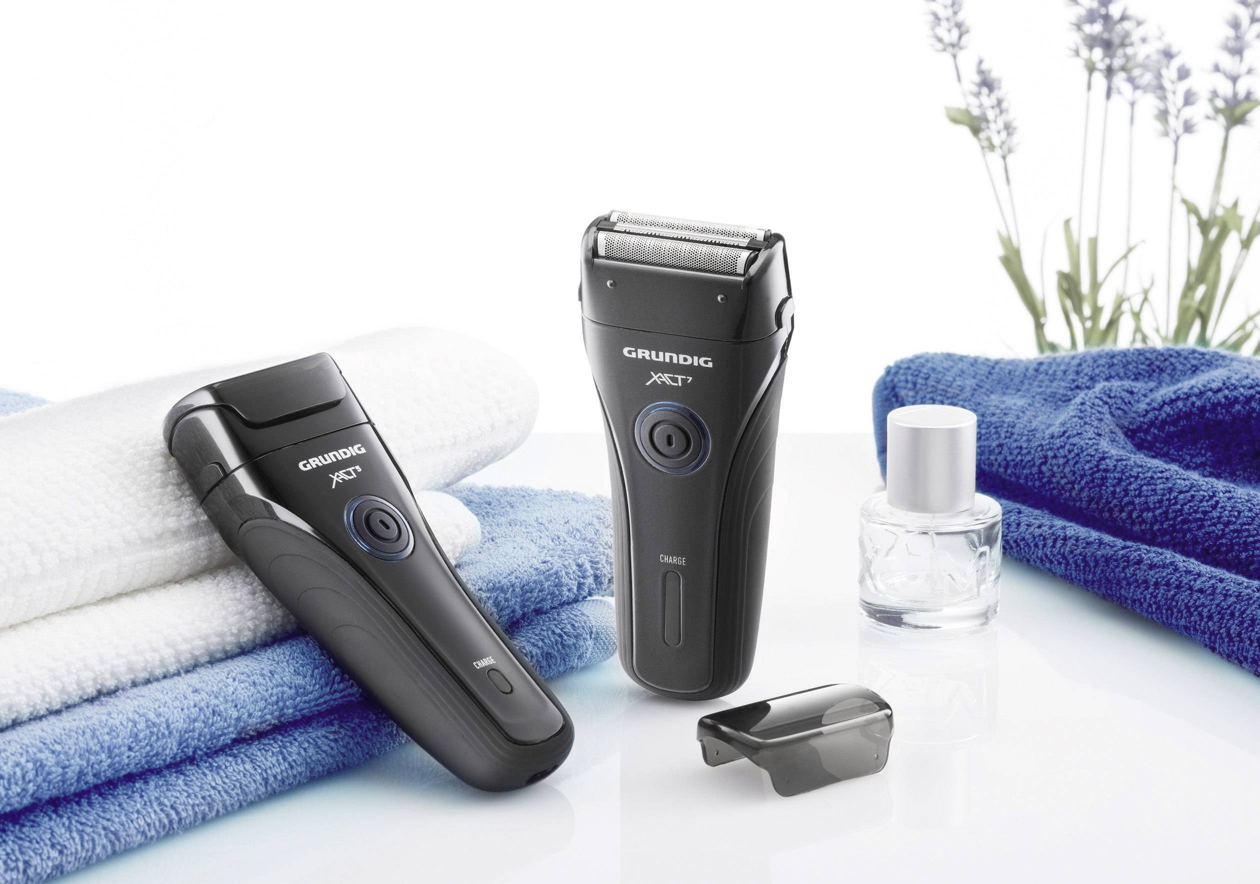 Elektrorasierer-Set mit zwei schwarzen Rasierern, Handtüchern und Lavendelzweig in einem Badezimmer. Perfekt für eine gründliche Rasur.