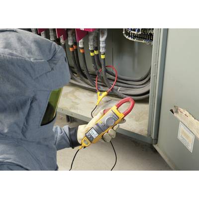 Eine Person in Schutzkleidung misst mit einem digitalen Multimeter die Spannung eines elektrischen Schaltschrankes. Sicherheitsvorkehrungen werden beachtet.