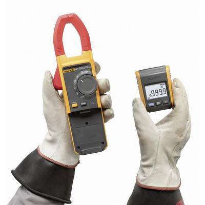 Ein Paar behandschuhte Hände hält eine orangefarbene Stromzange und ein separates Display. Das Display zeigt '9999.9'.