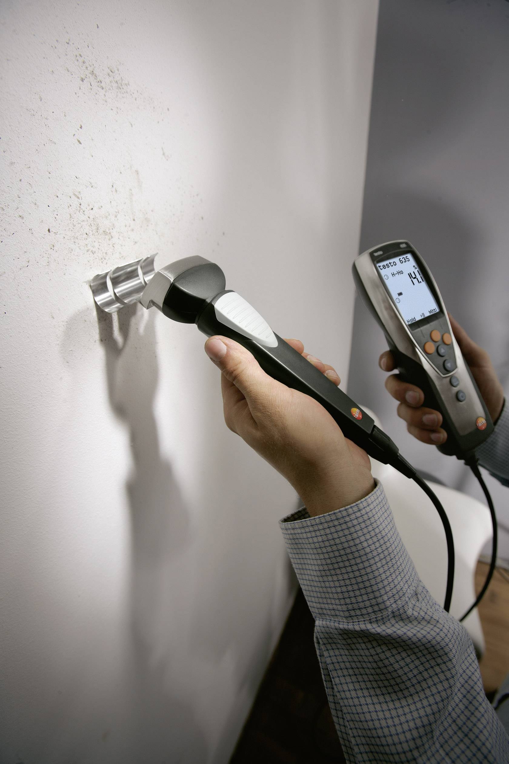 Eine Person misst die Wanddicke mit einem Ultraschallgerät. Das Display zeigt den gemessenen Wert an.