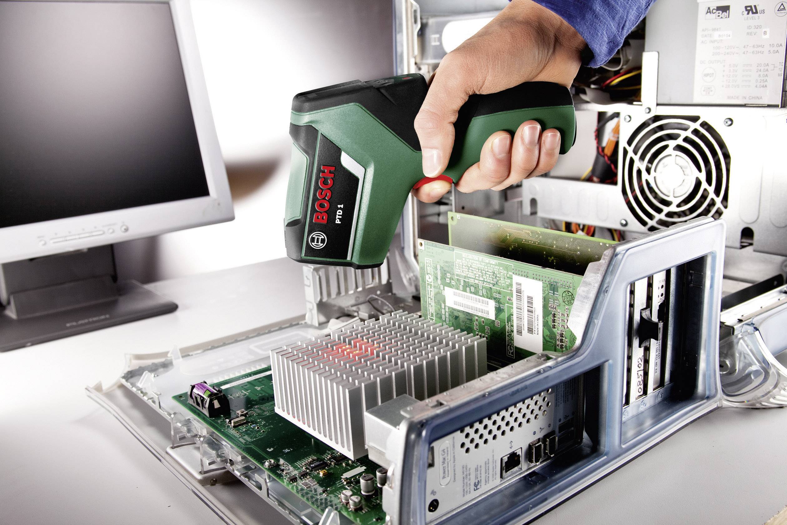 Eine Hand hält ein Bosch-Werkzeug über das offene Innere eines Computers. Das Gerät scheint für Reparaturen oder Messungen verwendet zu werden.
