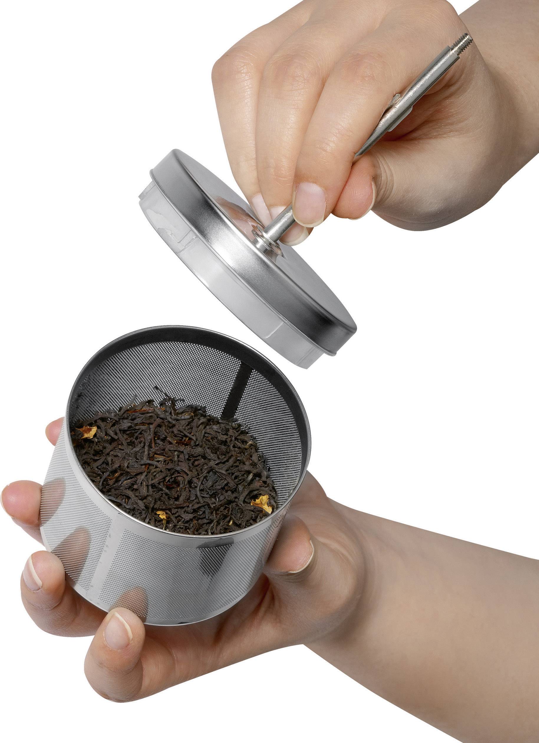 Eine Hand hält einen Teefilter mit schwarzem Tee, während die andere Hand den Deckel aufsetzt.