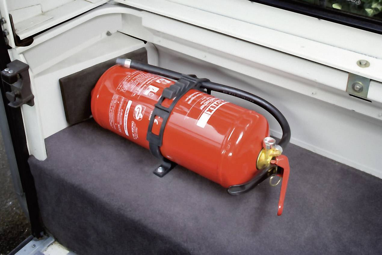 Feuerlöscher in einem Fahrzeug, sicher befestigt in einer Halterung im Kofferraum.