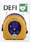 Tragbarer Defibrillator in einer transparenten Box, mit grünem Herzsymbol und Blitz. Aufschrift: 'DEFI'.