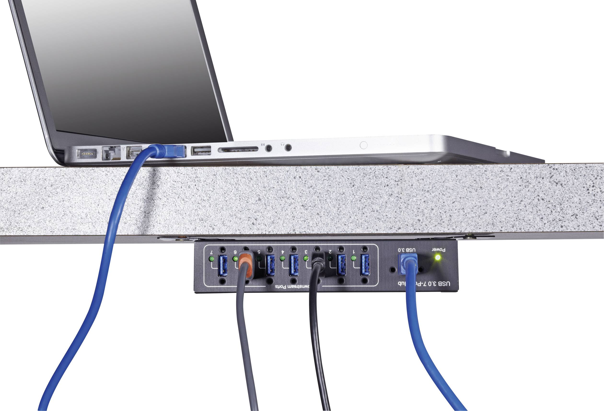 Ein Laptop ist auf einem Tisch und mit mehreren Kabeln an einen USB-Hub angeschlossen, der unter dem Tisch befestigt ist.