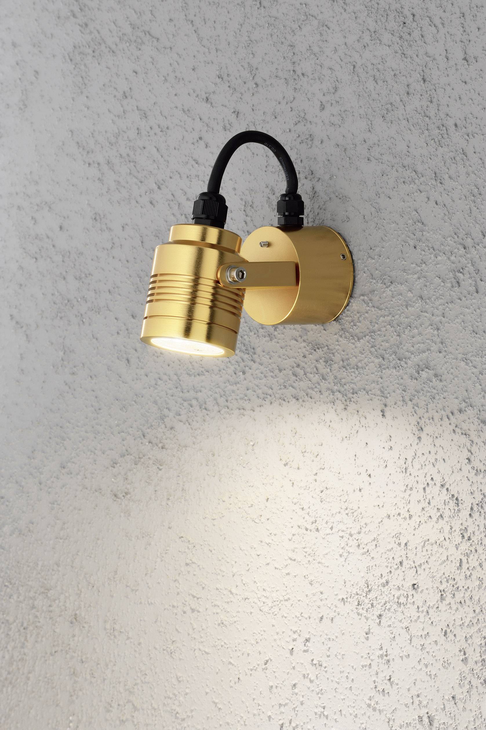 Goldene Wandleuchte mit LED-Licht strahlt nach unten auf eine strukturiere, graue Wand. Kabel führt von der Leuchte zur Wandmontage.