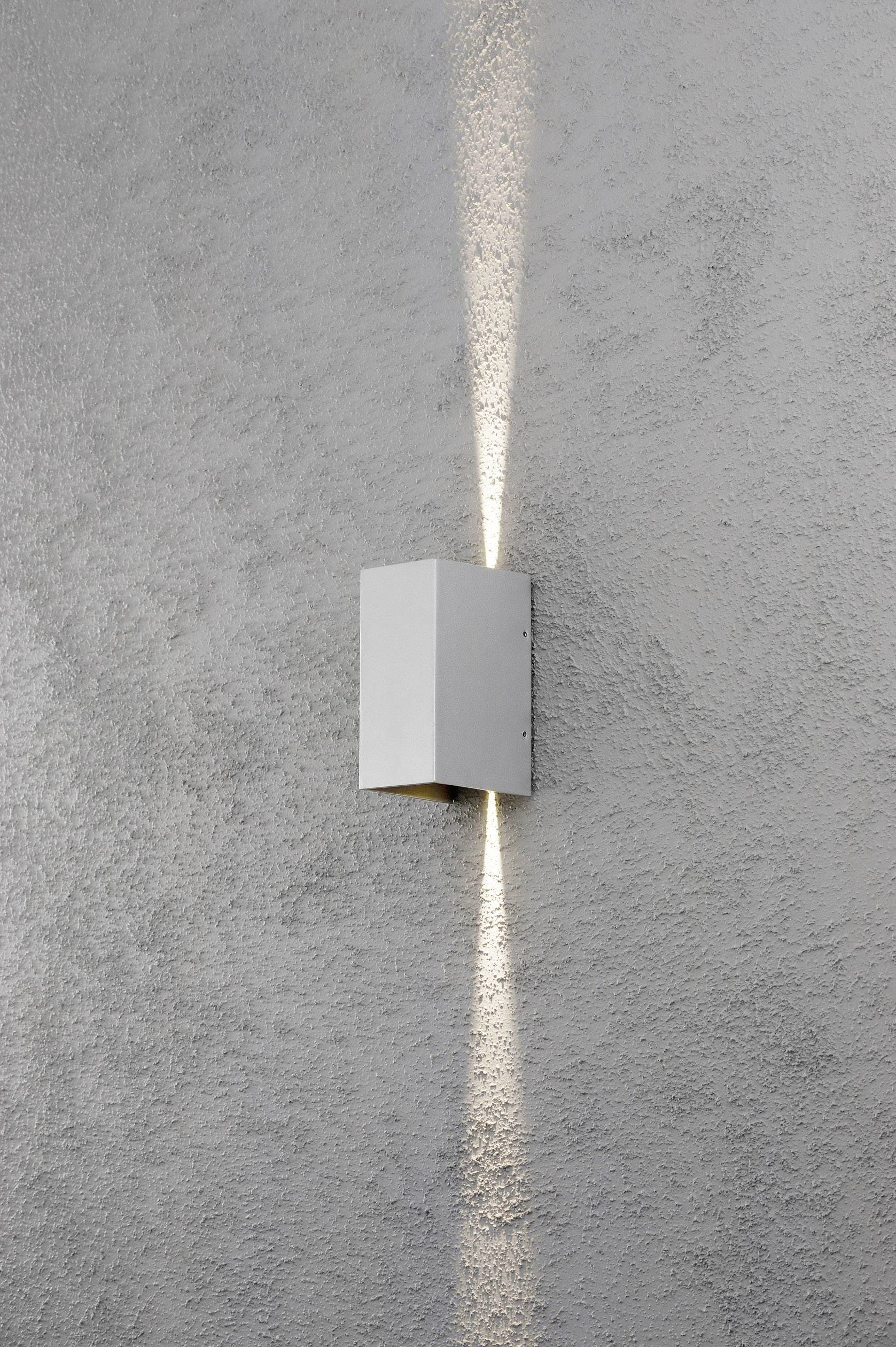 Weiße Außenwandleuchte, die sowohl nach oben als auch nach unten auf eine graue Betonwand strahlt.