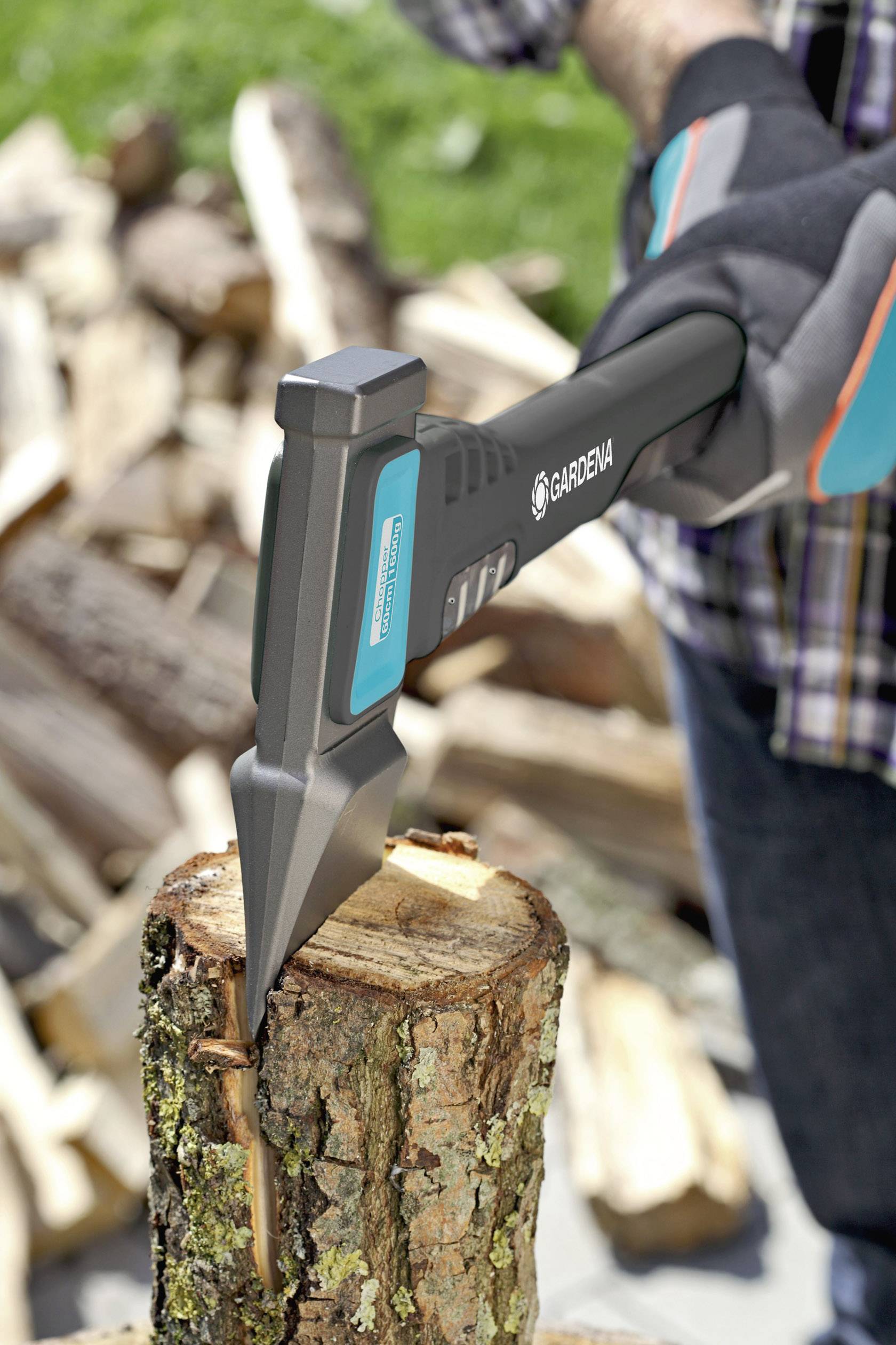 Eine Person spaltet Holzscheite mit einer Axt auf einem Baumstumpf. Die Umgebung zeigt gestapelte Holzscheite im Hintergrund.