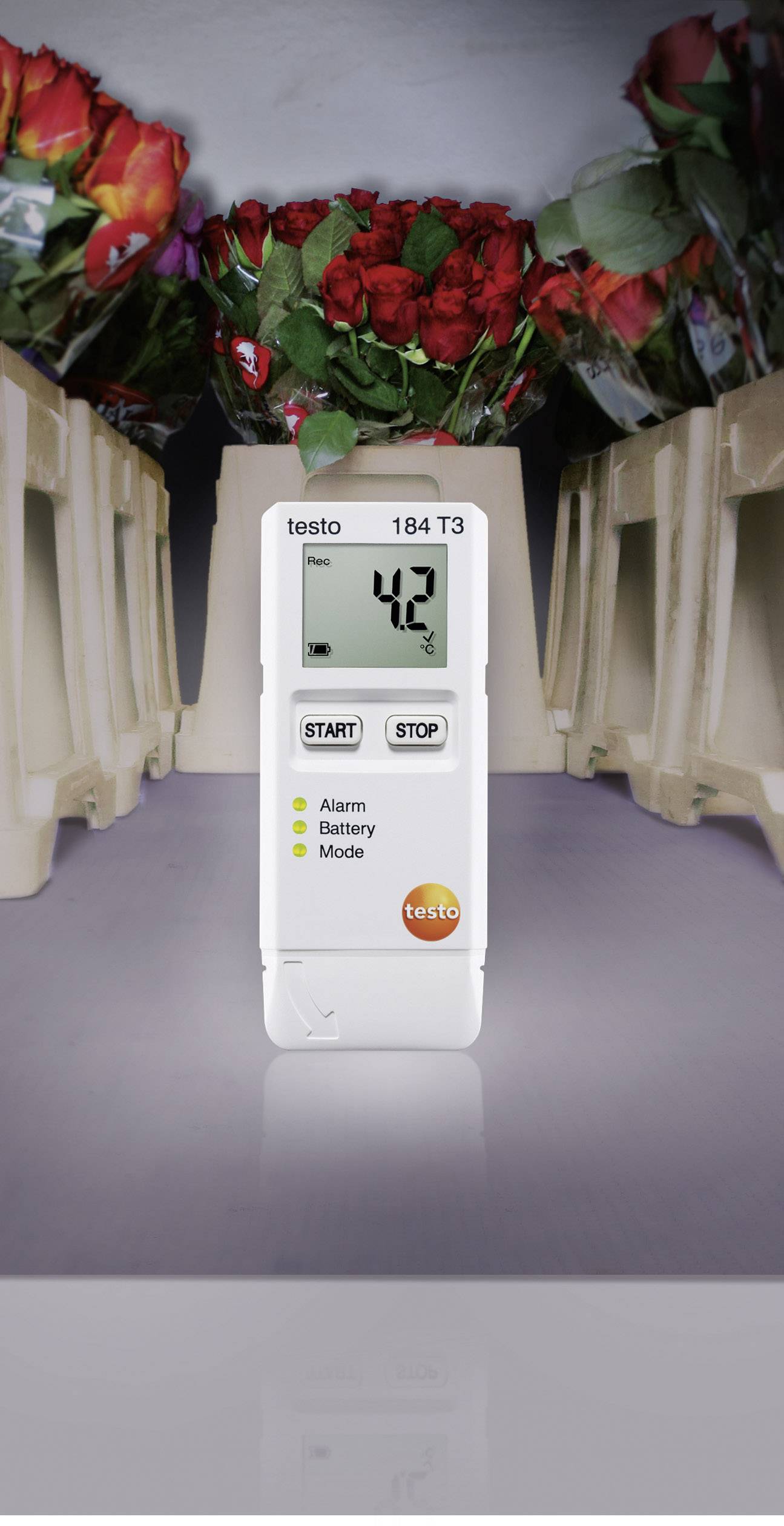 Ein digitaler Temperatur-Datenlogger zeigt '42' an. Im Hintergrund sind Blumenkisten zu sehen.