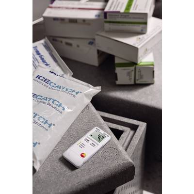 Ein digitales Thermometer zeigt 4,3 Grad Celsius an und liegt auf einer Isolierbox mit Kühlpackungen und Medikamentenkartons im Hintergrund.