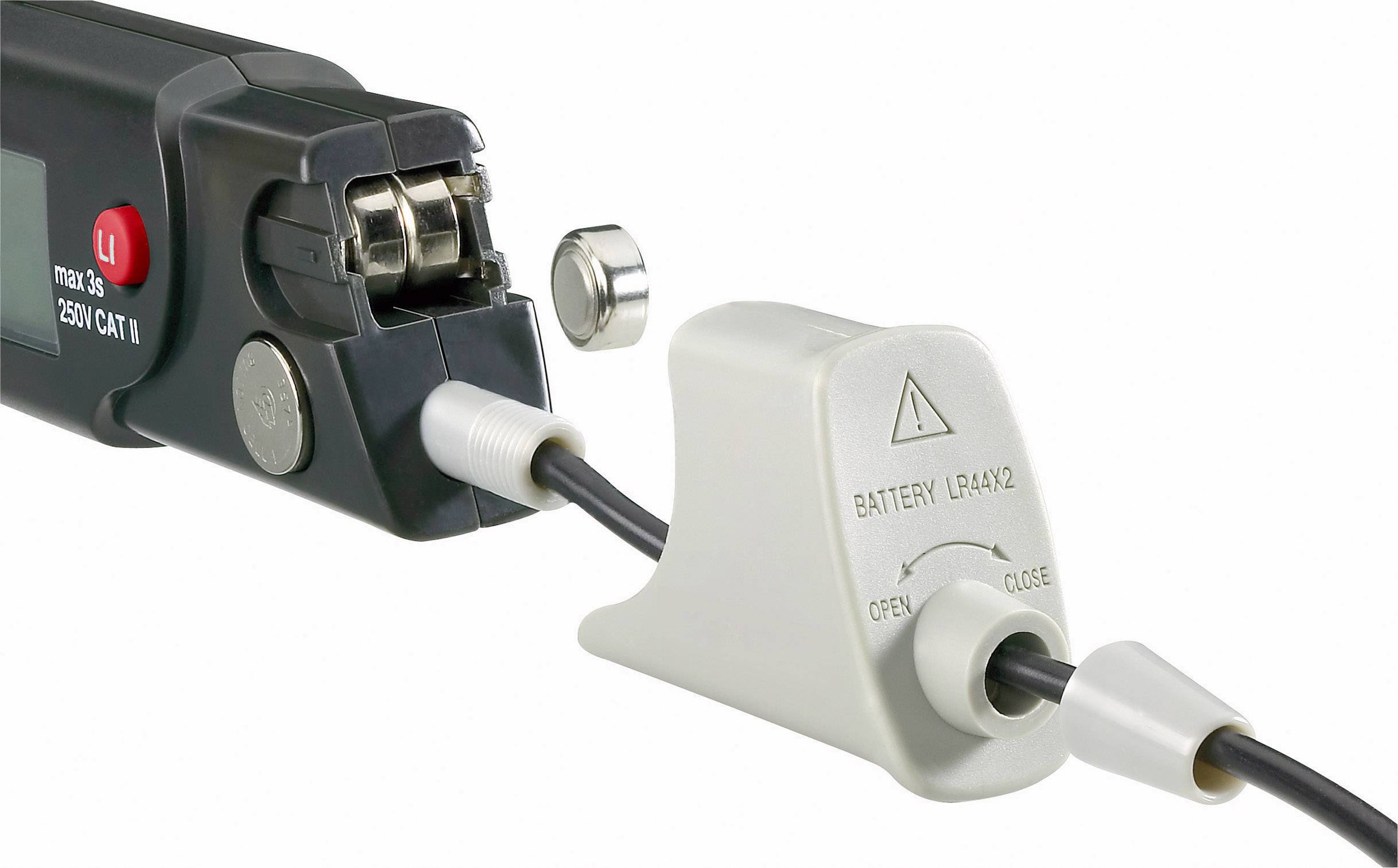 'Nahaufnahme eines Geräts mit angeschlossenem Kabel und abnehmbarem Batteriedeckel. Warnhinweise auf dem Batteriefach.'