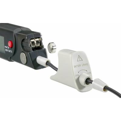 'Nahaufnahme eines Geräts mit angeschlossenem Kabel und abnehmbarem Batteriedeckel. Warnhinweise auf dem Batteriefach.'