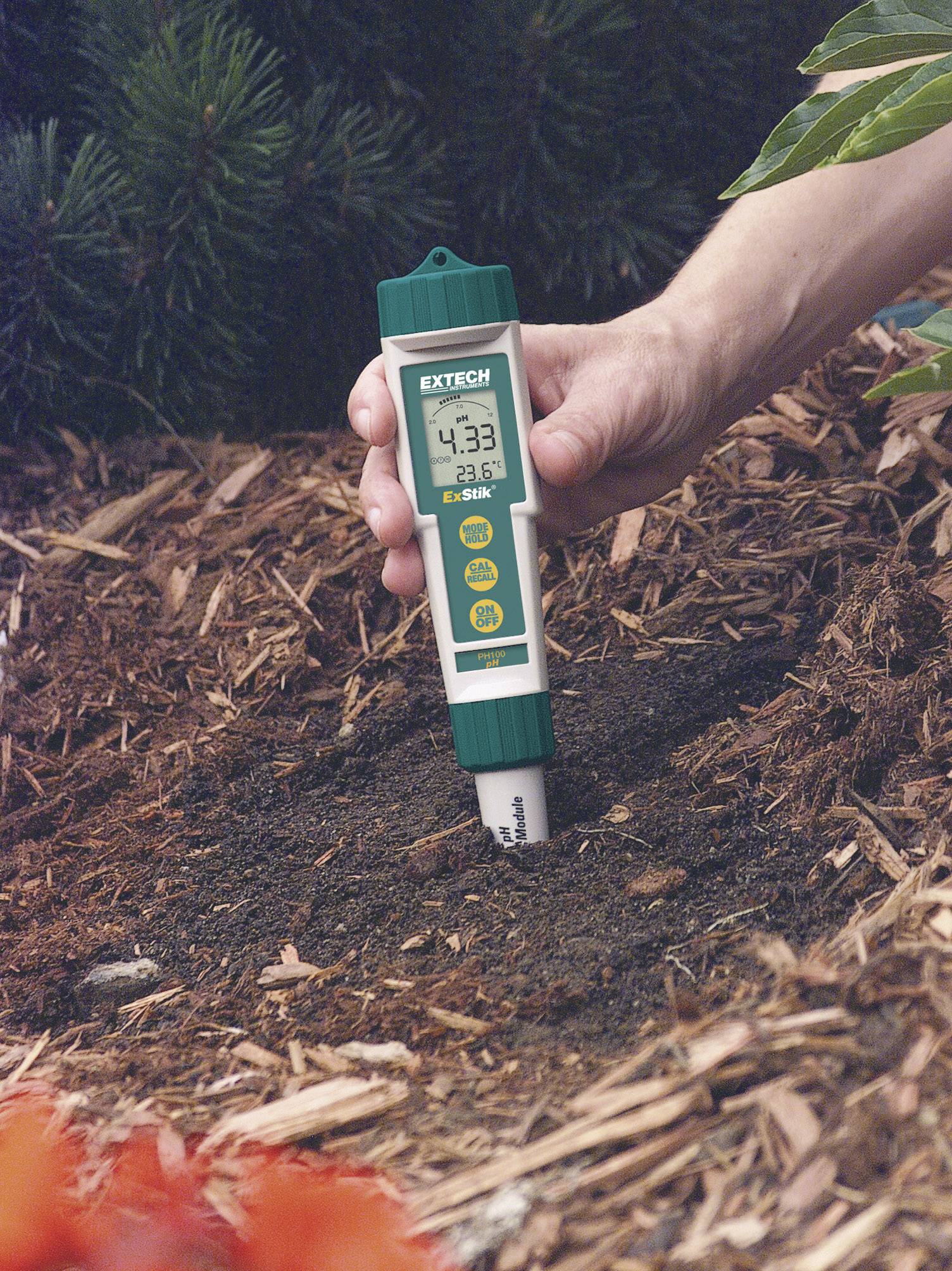 Eine Hand misst den pH-Wert des Bodens im Garten mit einem digitalen pH-Meter. Der angezeigte Wert ist 4,33 bei 23,6 Grad Celsius.