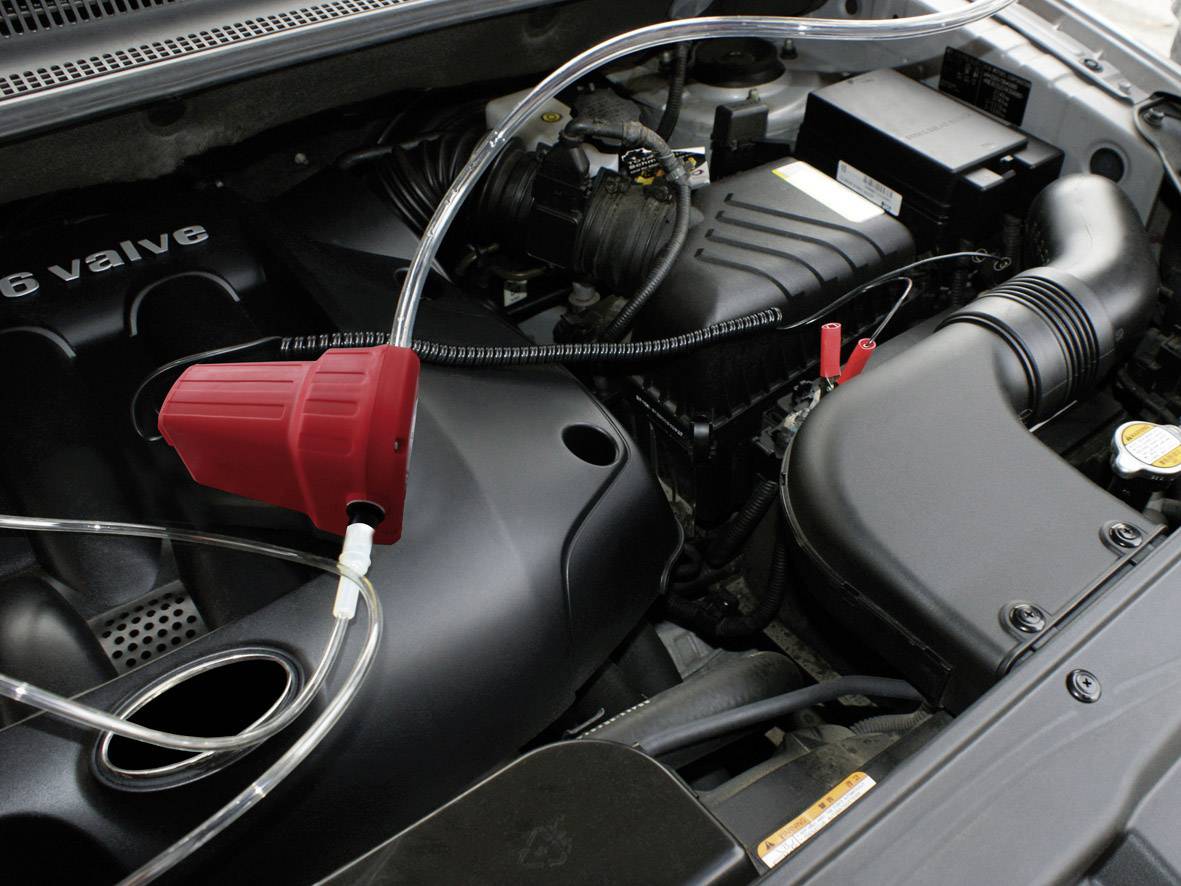 Ein Automotor mit einem roten Trichter und einem transparenten Schlauch, der für die Befüllung von Flüssigkeit verwendet wird.