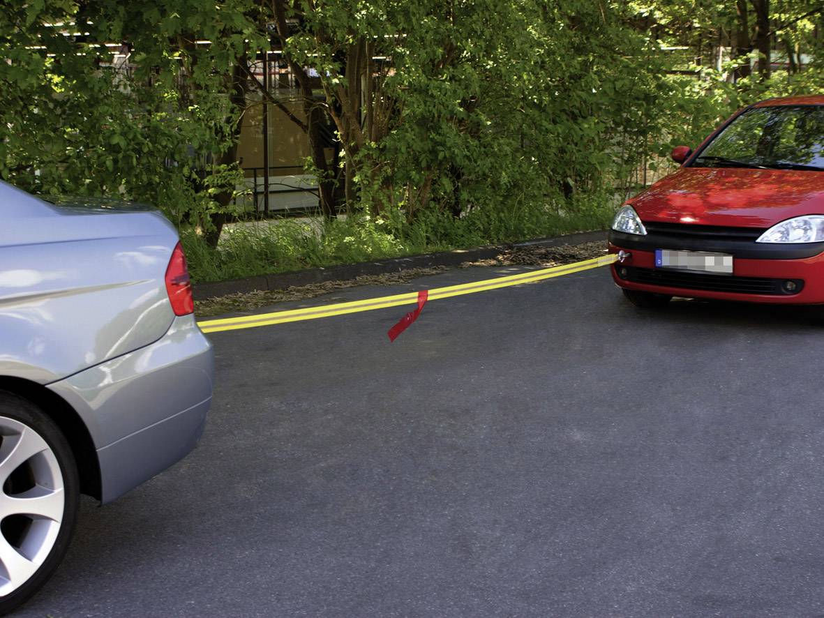 Ein graues Auto fährt auf ein rotes Auto zu. Beide Autos sind auf einer schmalen Straße mit Bäumen im Hintergrund.