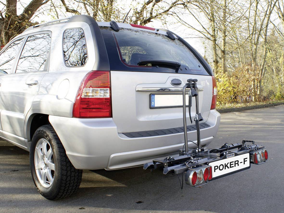 Silberner SUV mit montiertem Fahrradträger 'POKER-F' am Heck, auf einem Parkplatz in einer herbstlichen Umgebung.