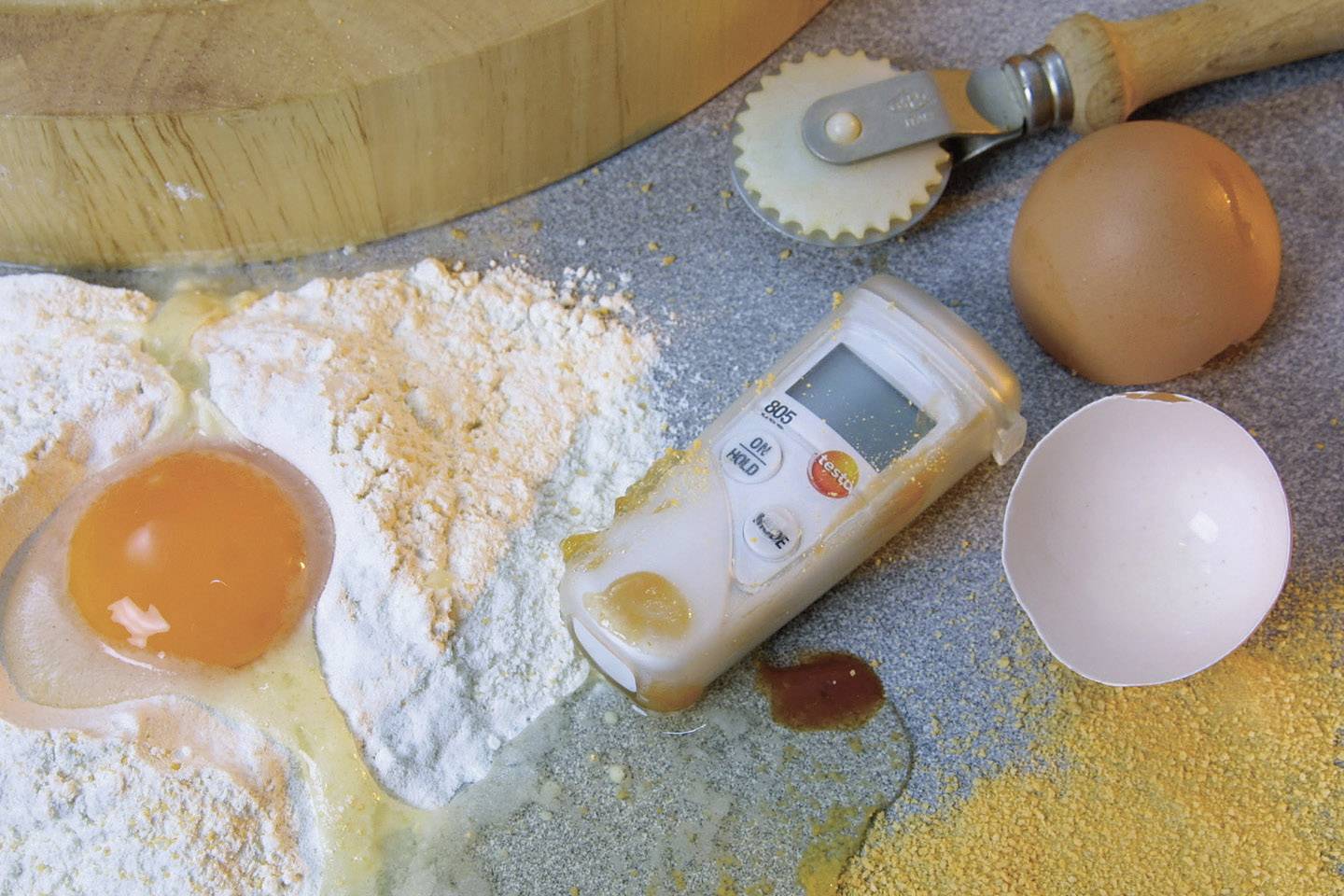Ein Ei, Mehl und ein digitales Küchenthermometer auf einer Arbeitsfläche; Symbolisiert das Backen.