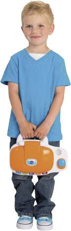 Ein Kind in blauem T-Shirt und Jeans hält lächelnd ein orange-weißes elektronisches Spielzeug in den Händen.